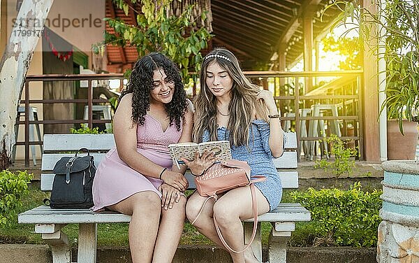 Zwei hübsche Mädchen lesen auf einer Bank  zwei hübsche Frauen lesen ein Buch auf einer Bank  Mädchen sitzen auf einer Bank und lesen