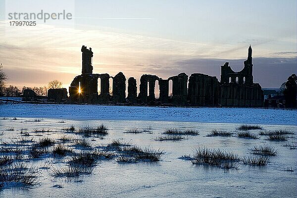 Ruinen der Abtei als Silhouette bei Sonnenuntergang  im Vordergrund gefrorenes Sumpfland  Byland Abbey  bei Helmsley  North Yorkshire  England  Dezember