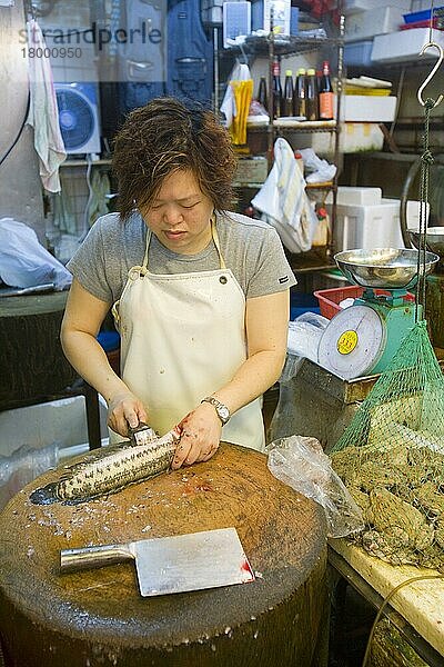 Frau bereitet Fisch neben Fröschen im Netz auf dem Fischmarkt zu  Kowloon  Hongkong  China  Asien