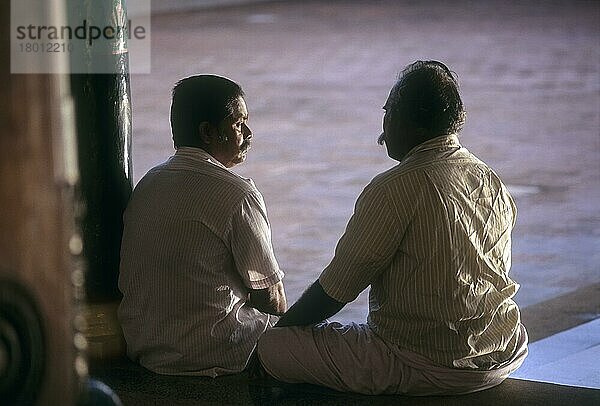 Freunde unterhalten sich auf einer Holzbank in einem Nattukottai Chettiar Haus in Kanadukathan  Chettinad  Tamil Nadu  Indien  Asien