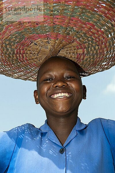 Lächelndes ruandisches Mädchen mit Korb auf dem Kopf