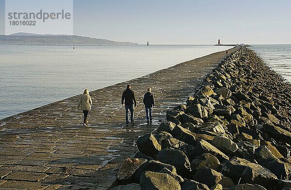 Menschen laufen auf Seemauer  die die Hafeneinfahrt schützt  Seemauer  die das Eindringen von Sand von der South Bull-Sandbank bei Sandymount verhindert  Große Südmauer  Hafen Dublin  Dublin Bay  Irland  November  Europa