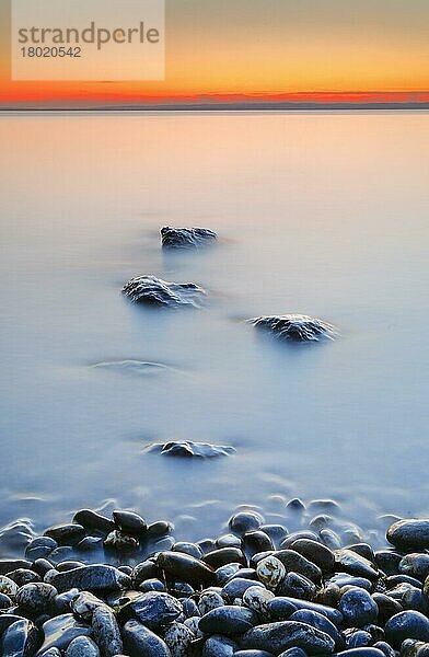 Blick von Arbon über den Bodensee bei Sonnenaufgang mit Steinen im Vordergrund