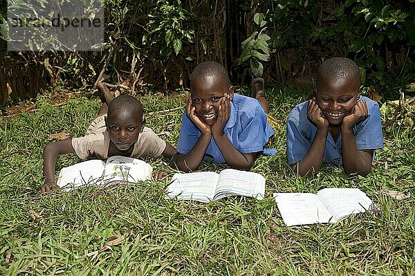 Lächelnde ruandische Kinder beim Lesen von Schulbüchern. Ruanda