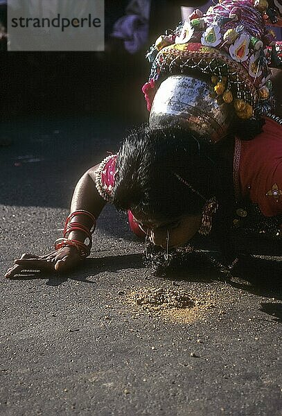 Eine Volkstänzerin hebt die Nadel während des Pongal-Festes in Madurai  Tamil Nadu  Indien  an den Augenwimpern vom Boden auf  Asien