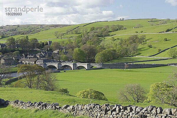 Ansicht einer fünfbogigen Steinbrücke über den River Wharfe  Trockenmauer  Weide  Bäume und Dorf  Burnsall  Wharfedale  Yorkshire Dales N. P. North Yorkshire  England  Mai