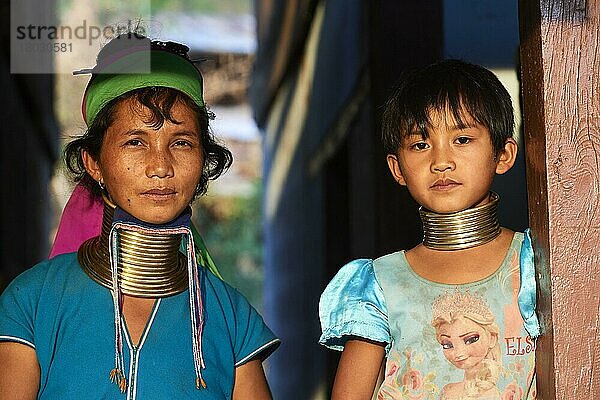 Bildnis einer Frau aus Kayan Lahwi mit Messinghalswicklung und traditioneller Kleidung. Das junge Mädchen  ihre Tochter  trägt ebenfalls die traditionellen Halsschleifen  jedoch kleiner und ihrem Alter angepasst (8 Jahre alt)  Pan Pet Region  Kayah State  Myanmar  Asien
