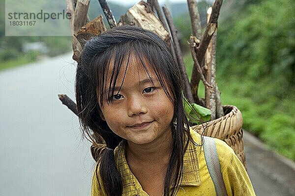 Nahaufnahme eines jungen Lao-Mädchens  das Feuerholz in einem Korb auf dem Rücken trägt  Provinz Luang Namtha  Nordlaos