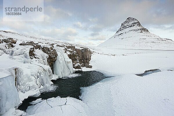 Der Berg Kirkjufell und der gefrorene Wasserfall Kirkjufellsfoss auf der Halbinsel Snæfellsnes im Schnee im Winter  Island  Europa