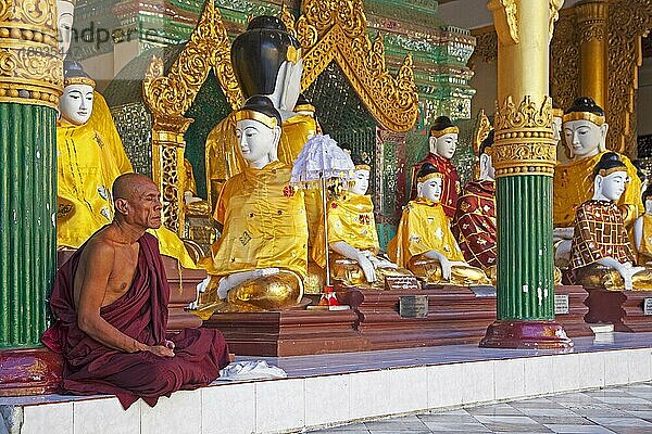 Buddhistischer Mönch beim Gebet vor Buddha-Statuen in der Shwedagon Zedi Daw Pagode in Yangon  Rangun  Myanmar  Asien