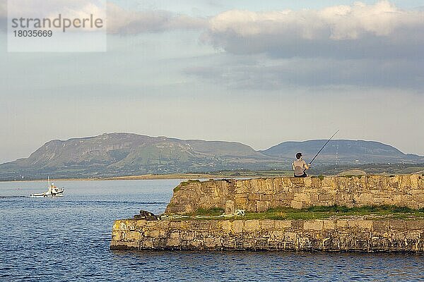 Mann beim Angeln an einem Sommerabend  während das Boot aufs Meer hinausfährt. Sligo  Irland  Europa