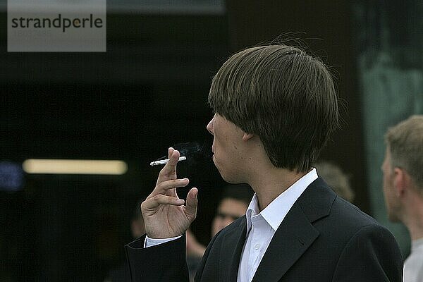 Wegschauender junger Mann im Anzug hält Zigarette in der Hand  Deutschland  Europa
