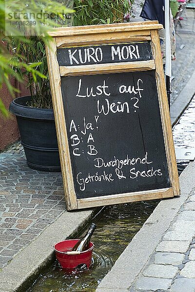 Tafel mit Aufschrift Lust auf Wein? vor einem Restaurant  im Vordergrund eine Weinflasche im Eimer zur Kühlung im Bächle  Freiburg im Breisgau  Baden-Württemberg  Deutschland  Europa