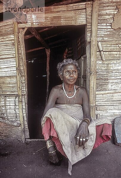 Alte Frau vom Stamm der Mudunga  die vor ihrer Hütte in einem Stammesdorf in der Nähe des Silent Valley  Kerala  Indien  sitzt  Asien