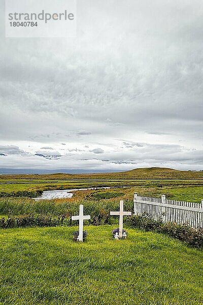 Friedhof  zwei Gräber nebeneinander  weiße Holzkreuze auf einer Wiese mit Zaun  Fluss am Horizont  Textfreiraum  Nordwestisland  Island  Europa