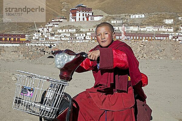 Junger Mönch fährt Roller vor dem tibetischen Kloster Sershu Dzong im Dorf Sershu  Serxu  Provinz Sichuan  China  Asien