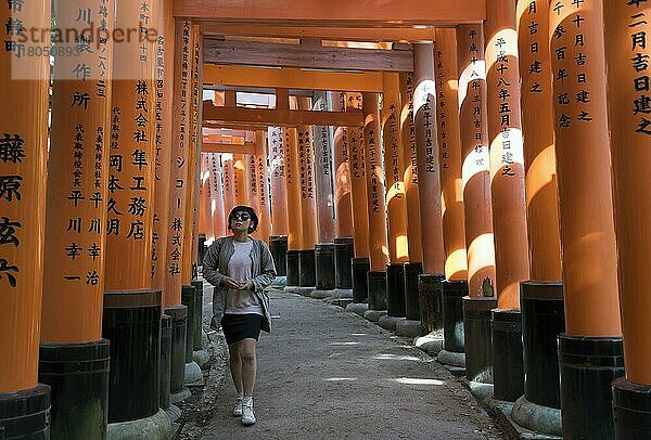 Junge Frau auf einem mit Torii-Toren gesäumten Weg  Fushimi Inari-taisha-Schrein  Kyoto  Japan  Asien
