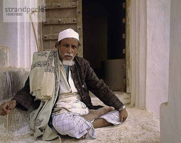 Mann in traditioneller Kleidung sitzt vor der Haustüre  Jemen  Asien