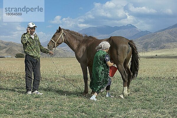 Kasachischer Mann mit Handy und kasachische Frau beim Melken einer Stute  Gabagly-Nationalpark  Shymkent  Südregion  Kasachstan  Zentralasien  Nur für redaktionellen Gebrauch  Asien