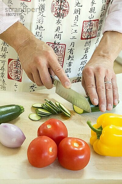 Männlicher Erwachsener  der in der Küche verschiedene Gemüsesorten schneidet