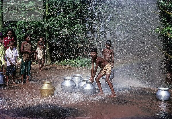 Silberne Dusche. Jungen spielen mit dem Spritzwasser aus der undichten Trinkwasserleitung in der Nähe von Coimbatore  Tamil Nadu  Indien  Asien