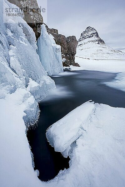 Der Berg Kirkjufell und der gefrorene Wasserfall Kirkjufellsfoss auf der Halbinsel Snæfellsnes im Schnee im Winter  Island  Europa