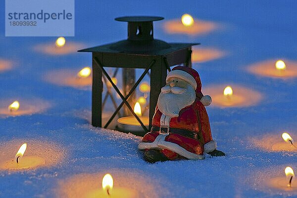 Weihnachtsmann und Laterne im Schnee  mit brennenden Kerzen