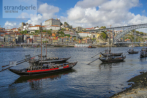 Blick auf die Brücke Dom Luis I. über den Fluss Douro und die Rabelo-Boote in einer Reihe mit bunten Gebäuden  UNESCO-Weltkulturerbe  Porto  Norte  Portugal  Europa