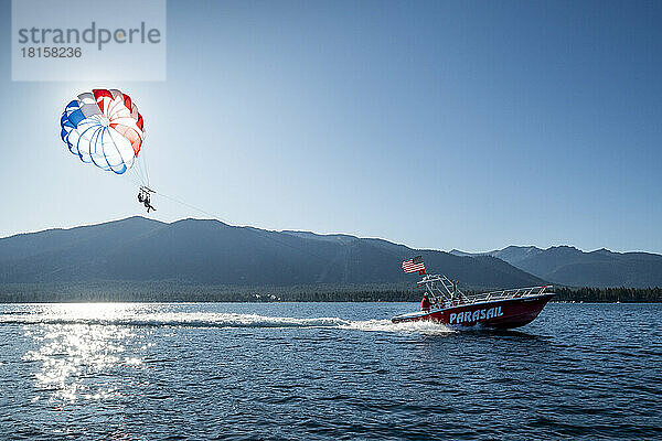 Ein rotes Boot schleppte an einem Sommermorgen zwei Parasailer.