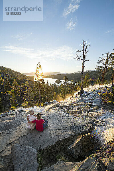 Ein Mann und eine Frau entspannen sich bei Sonnenaufgang auf dem Gipfel der Eagle Falls.