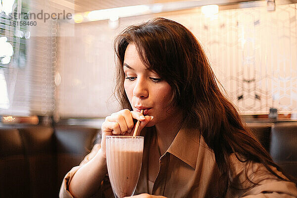 Junge Frau trinkt Schokoladenmilchshake im Restaurant