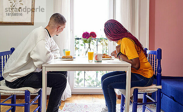 Gemischtes Paar beim Frühstück zu Hause