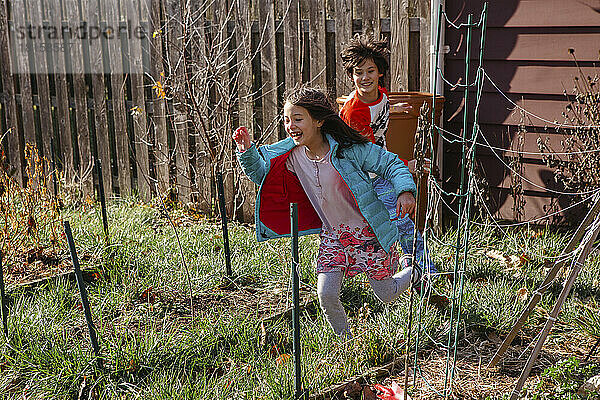 Zwei glückliche Kinder spielen im Sonnenschein im Hinterhof Garten