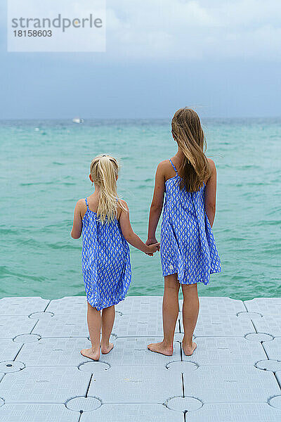 Zwei Schwestern schauen auf das blaue Meer.