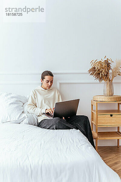 Junges Mädchen schaut einen Film auf einem Laptop auf einem Bett in einer Brigg