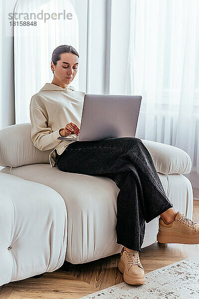Ein junges Mädchen arbeitet ferngesteuert an einem Laptop in einer hellen Wohnung