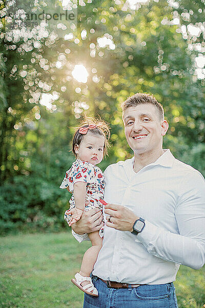 Kaukasischer Vater hält seine 1-jährige Tochter an einem Sommertag.