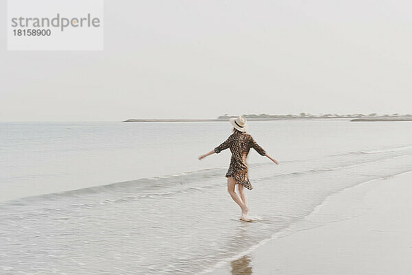 Junge Frau in Hütte und Strandkleidung am Strand  Bewegungseffekt