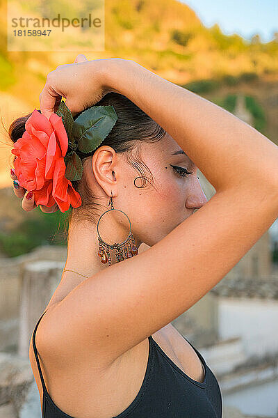 Frau steckt sich eine rote Blume ins Haar