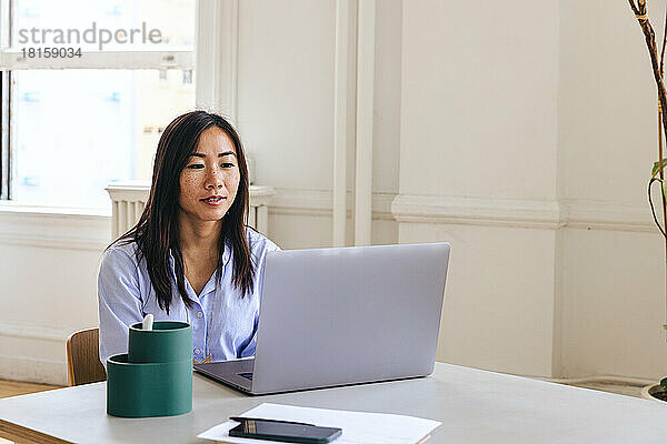 Unternehmerin mit Laptop auf dem Schreibtisch im Kreativbüro