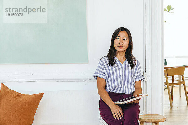 Porträt einer selbstbewussten Geschäftsfrau mit digitalem Tablet sitzend