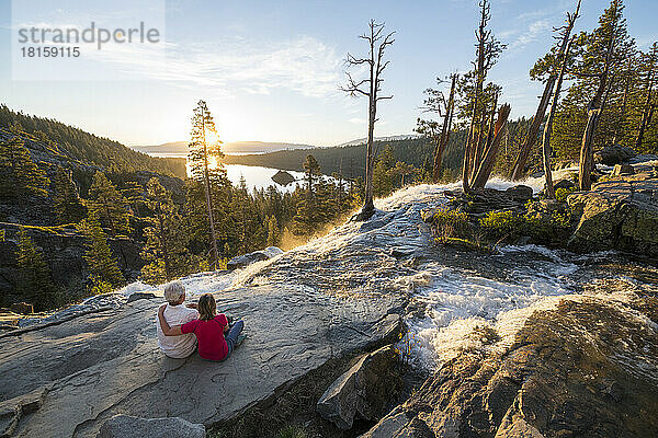 Ein Mann und eine Frau entspannen sich bei Sonnenaufgang auf dem Gipfel der Eagle Falls.