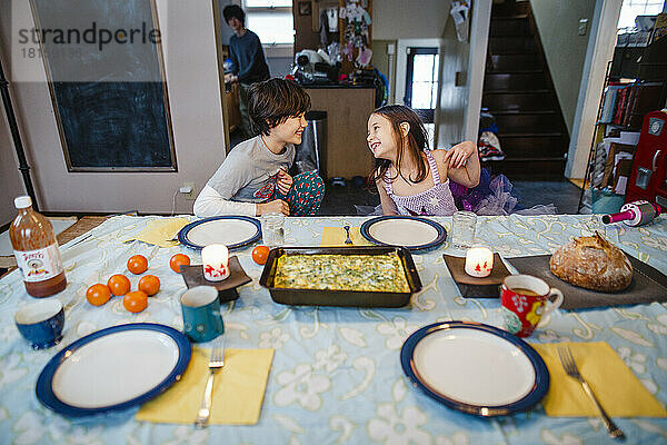 Zwei glückliche Kinder setzen sich zu Hause an den Frühstückstisch