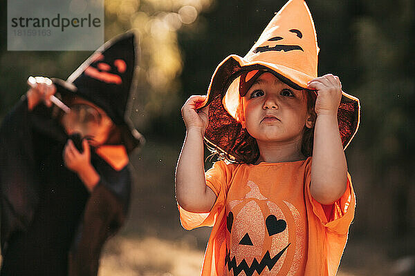 Zwei kleine Mädchen feiern Halloween im Naturkürbis