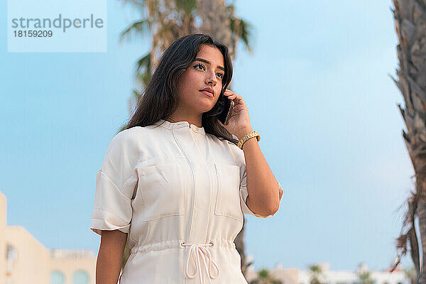Business junge lateinische Frau spricht durch sein Mobiltelefon draußen