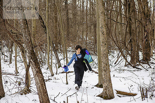 Ein Junge in Schneeausrüstung wandert im Winter durch den Wald