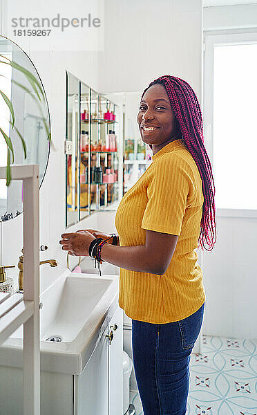 Junge afroamerikanische Frau wäscht sich im Badezimmer zu Hause die Hände