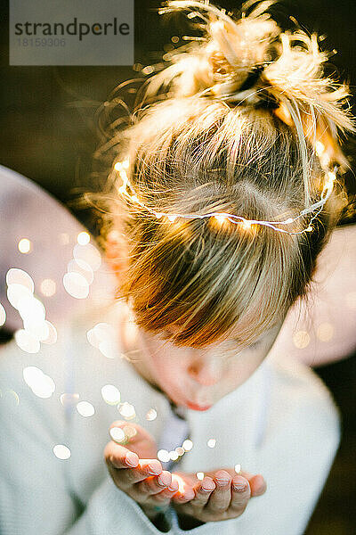 Blondes Mädchen Kind in Engelsflügeln mit Feenstaub Lichtern