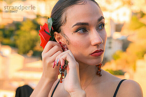 Frau steckt sich einen Ohrring ins Ohr. Flamenco-Stil