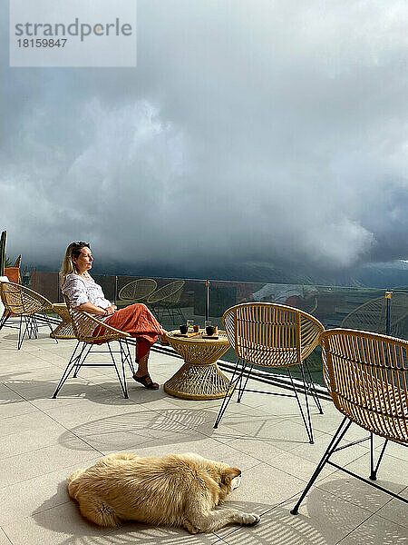 Schöne Frau entspannt auf der Terrasse eines Cafés mit Hund